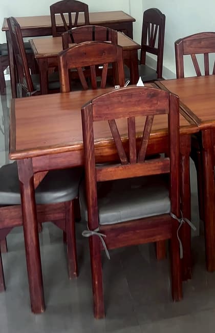 El desayunador: mesas de madera con sillas de respaldo calado y almohadones grises