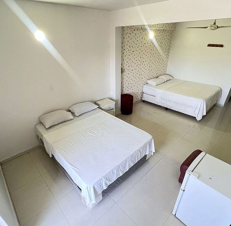 Habitación con dos camas, un frigobar y un sillón