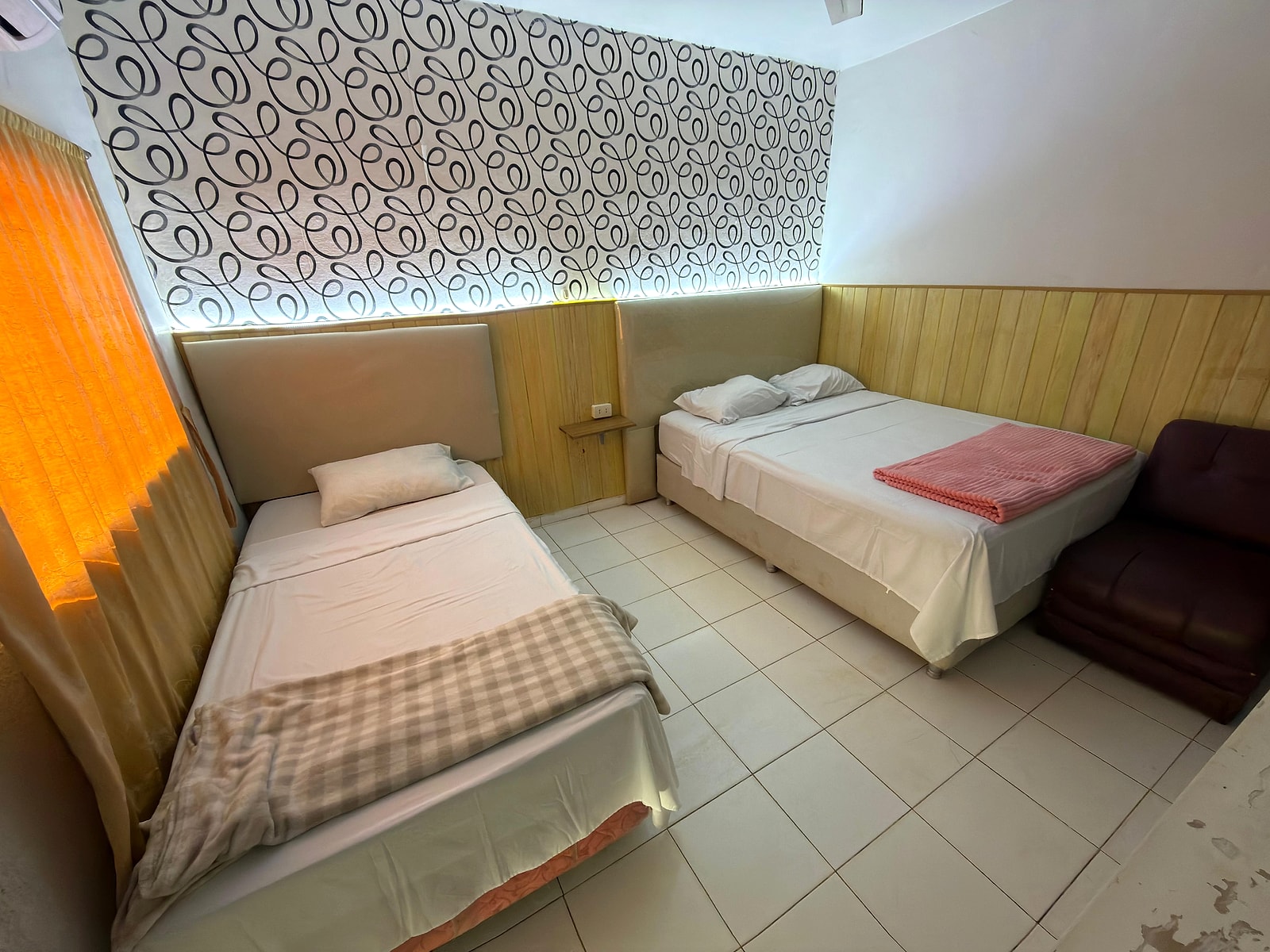 La familiar estándar: una cama matrimonial y otra de una plaza, con el papel tapiz en la pared