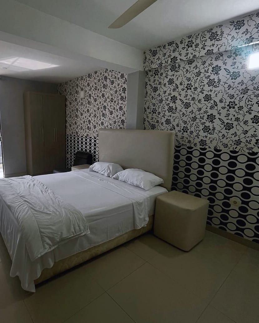 La suite: cama queen tendida, papel tapiz y luz de la ventana