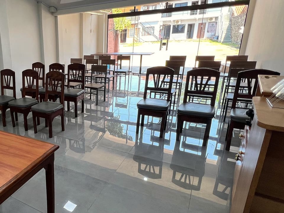 La sala de reuniones del hotel: sillas de madera en filas sobre un piso claro y un ventanal de vidrio al fondo